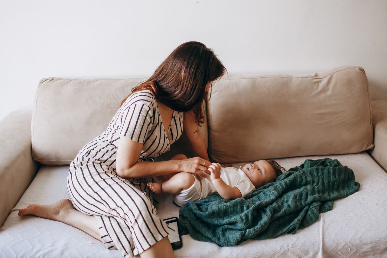 A serene moment of a mother and baby relaxing on a cozy sofa at home.