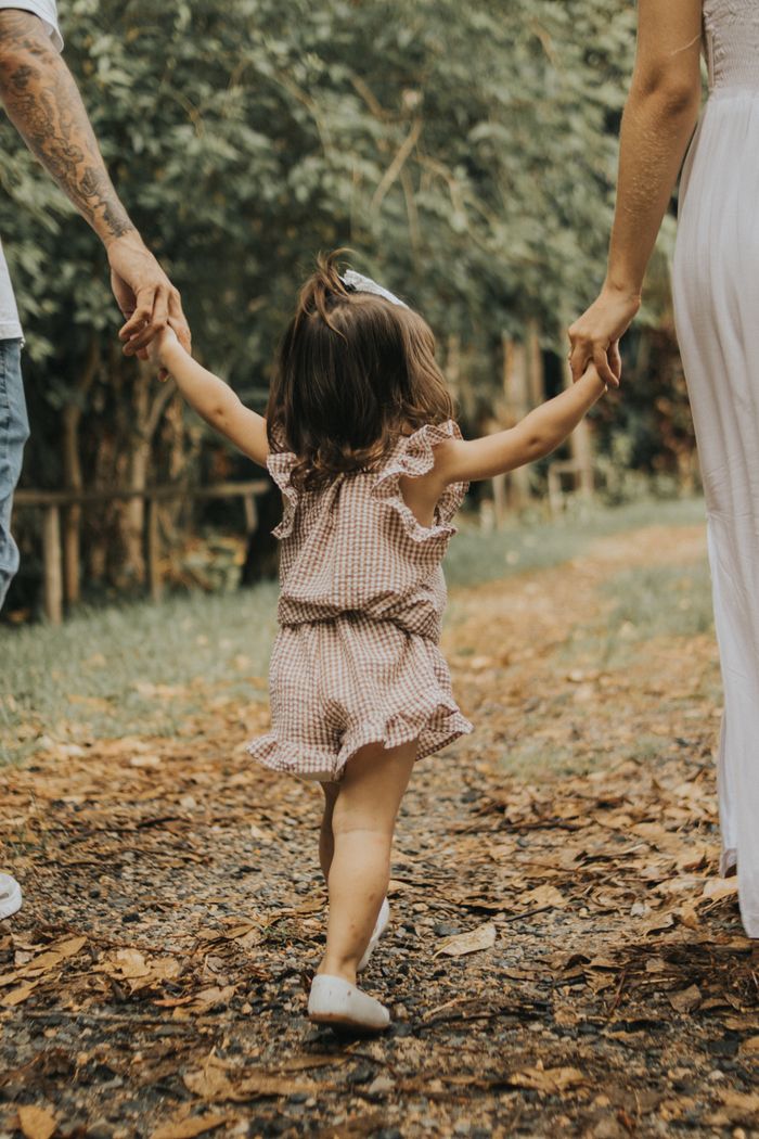 Child holding hands with parents on a peaceful nature walk.