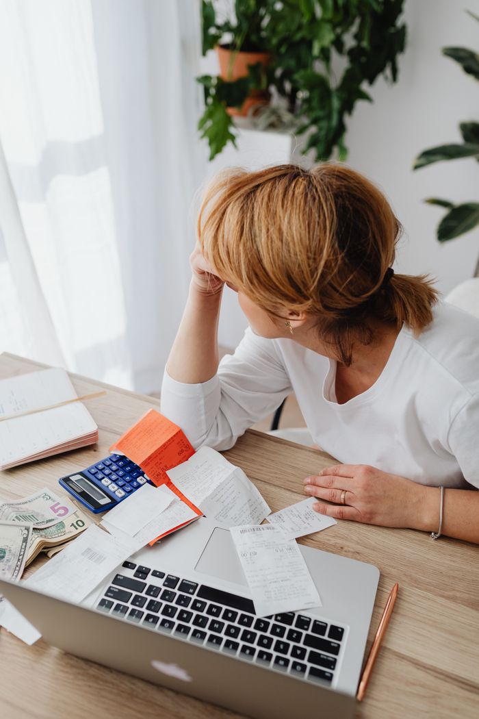 The Art of Drawing Readers In: Your attractive post title goes here A woman overwhelmed by bills and finances sits at a desk with a laptop and calculator.