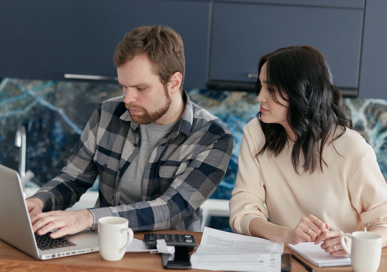 Mastering the First Impression: Your intriguing post title goes here A couple working together on financial planning at home, using a laptop and paperwork.